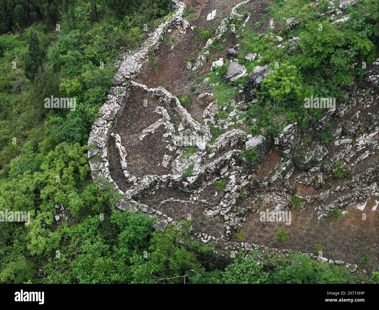 Qianxinan. 17 mai 2024. Une photo prise par un drone aérien le 17 mai 2024 montre une vue des ruines d'une ancienne ville datant de la dynastie Ming (1368-1644) au village de Pingzhai de la préfecture autonome de Bouyei-Miao de Qianxinan, dans la province du Guizhou au sud-ouest de la Chine. Le site apparaît de forme ovale vu d'en haut, couvrant une superficie d'environ 18 000 mètres carrés, avec plus de 900 mètres de murs de pierre restés. Crédit : Liu Xu/Xinhua/Alamy Live News Banque D'Images