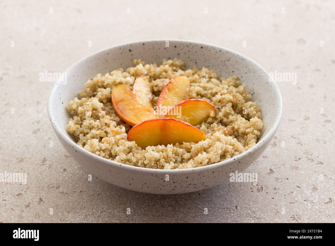 Quinoa avec tranche de pomme caramélisée sur un fond texturé beige. Plat sain végétalien Banque D'Images