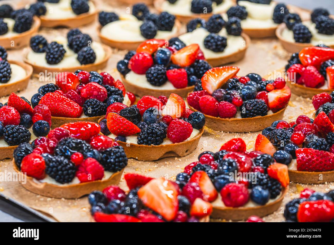 Tartelettes aux framboises, mûres, fraises, groseilles, bleuets sur un plateau, préparées en arrière-plan Banque D'Images