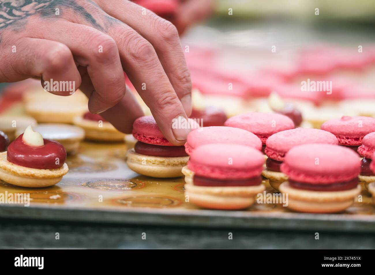 Mains de confiseur finissant les macarons roses Banque D'Images