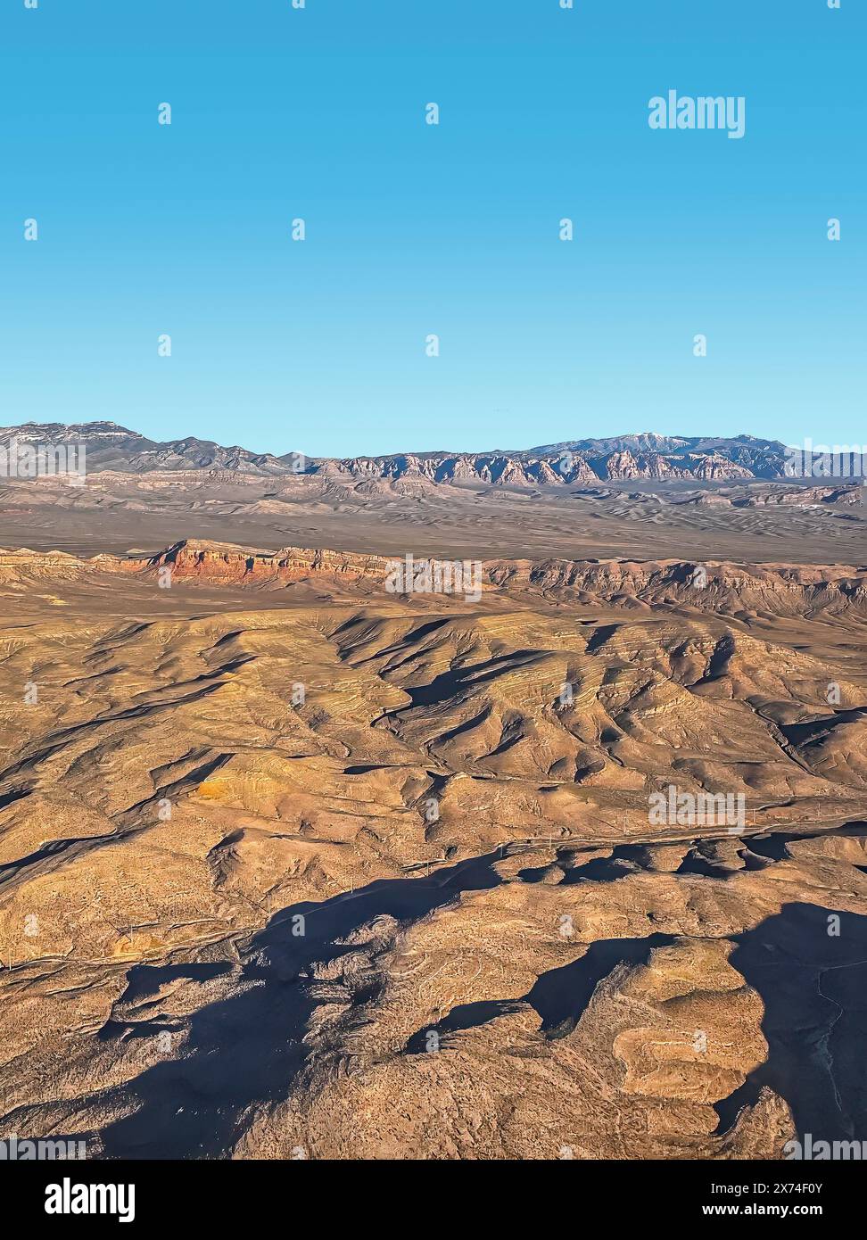 Parc national de la vallée de la mort, CA, États-Unis - 11 mai 2024 : vol au-dessus du paysage sec de pierre brune avec des chaînes de montagnes et des appartements sous le ciel bleu du matin. Noir Banque D'Images