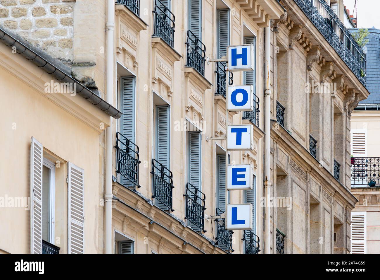 Panneau avec le mot 'HOTEL' écrit en lettres majuscules lumineuses sur la façade d'un bâtiment à Paris, France Banque D'Images