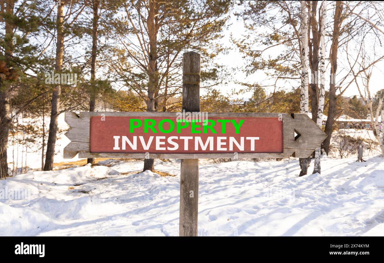 Symbole d'investissement immobilier. Mots conceptuels investissement immobilier sur un beau panneau routier en bois. Beau fond d'arbre de neige de forêt d'hiver. Relations commerciales Banque D'Images