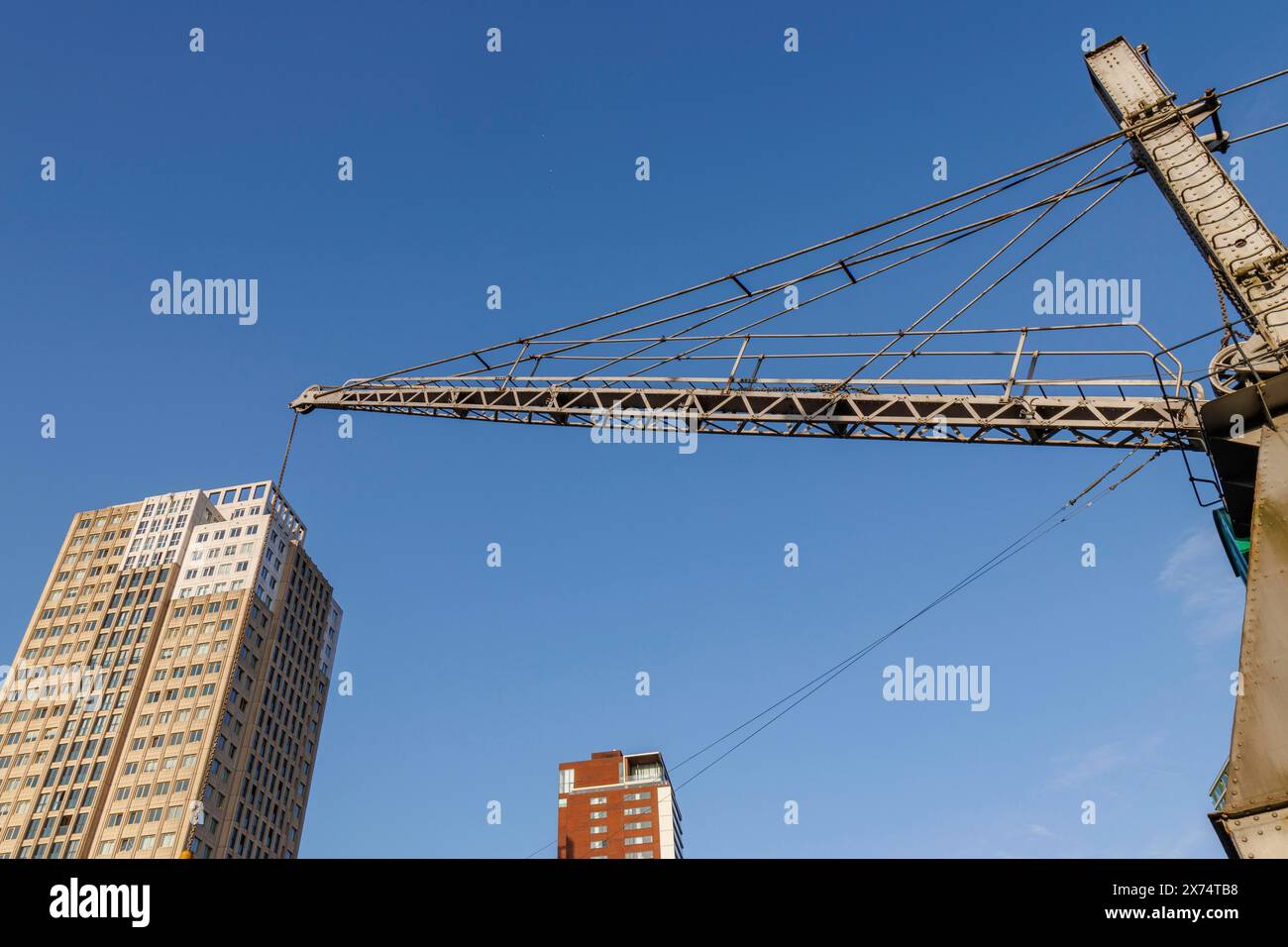 Une grue domine des gratte-ciels modernes sous un ciel bleu dans une scène de ville, un petit port dans une grande ville avec un phare et des maisons modernes, Rotterdam Banque D'Images