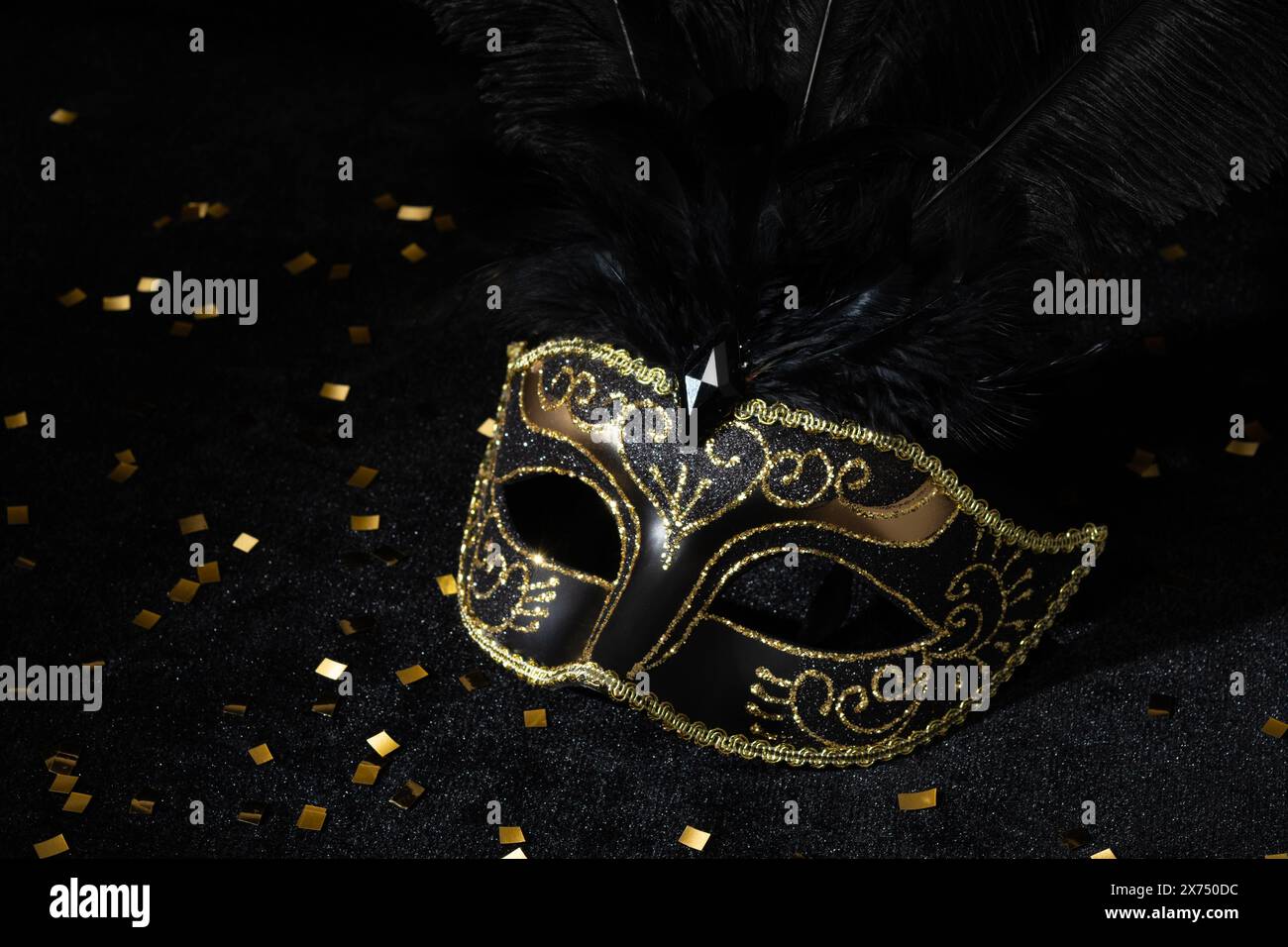 Masque d'or mascarade avec des plumes et des confetties sur fond noir. Banque D'Images