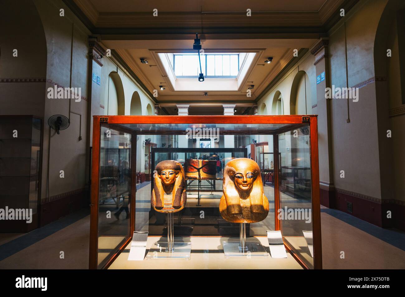 Des masques de sarcophage égyptiens antiques exposés au Musée égyptien du Caire, abrités dans une galerie éclairée avec des murs voûtés et des vitrines de protection Banque D'Images