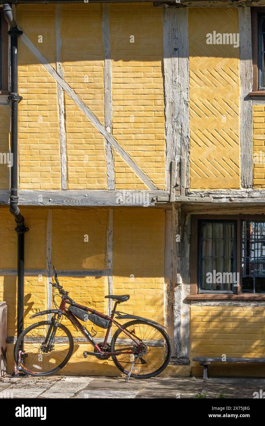 Vélo enchaîné à un tuyau d'évacuation contre le côté d'un bâtiment à ossature de bois jaune, Henley on Thames, Oxfordshire, Angleterre, Royaume-Uni Banque D'Images