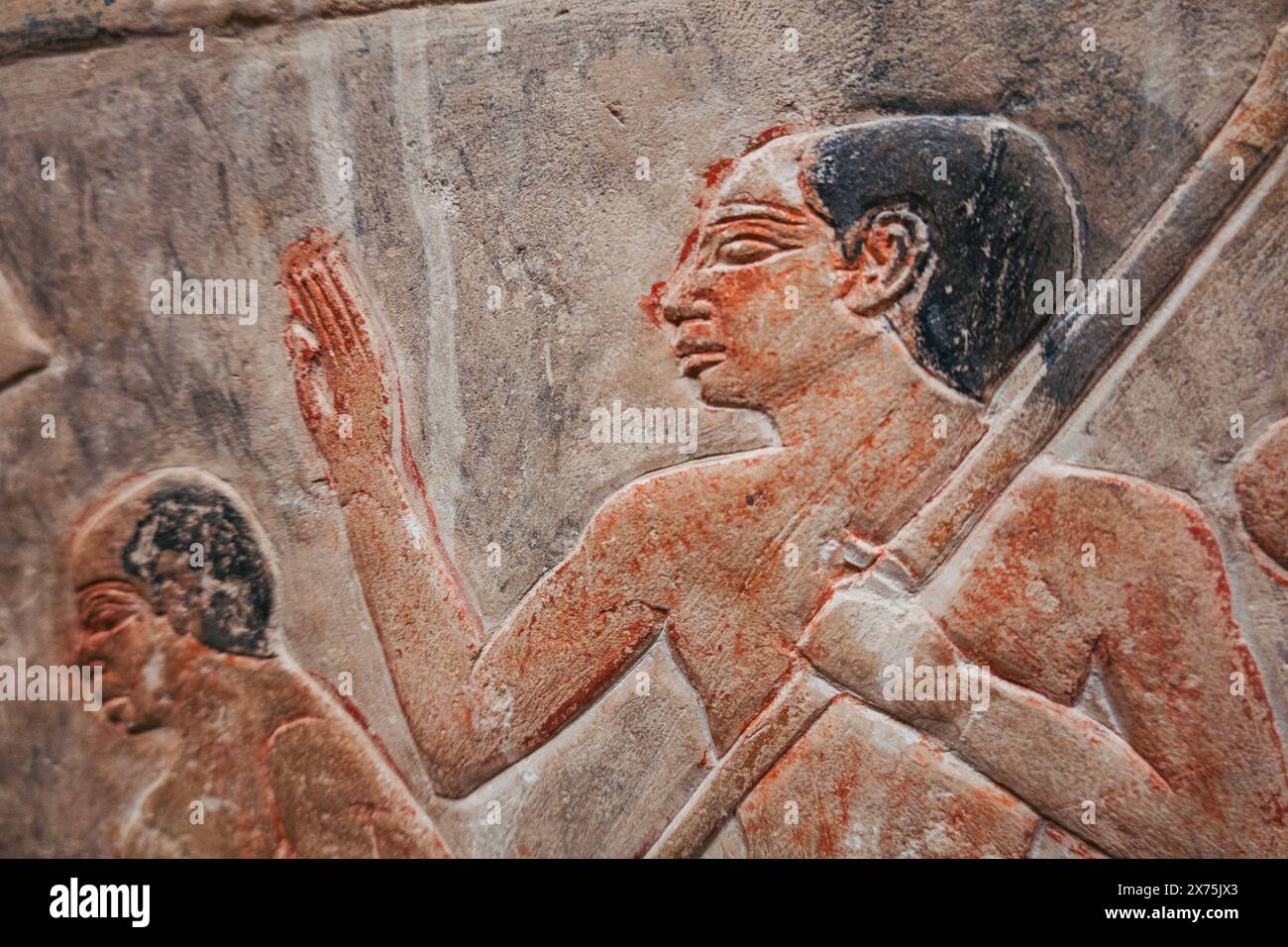 Gros plan d'un relief dans une tombe à Saqqara montrant une figure masculine avec un personnel, peut-être un ouvrier ou un accompagnateur, avec un pigment rouge encore visible Banque D'Images