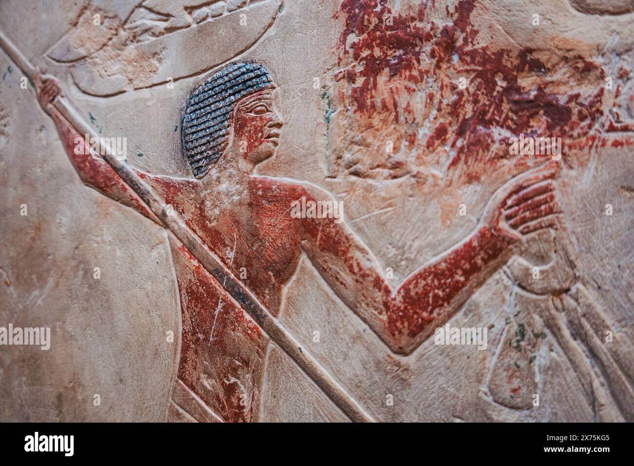 Relief peint d'une tombe de Saqqara montrant un ouvrier de l'ancien Empire tenant une lance et un oiseau, peut-être une partie d'une scène de chasse ou de chasse dans les marais Banque D'Images