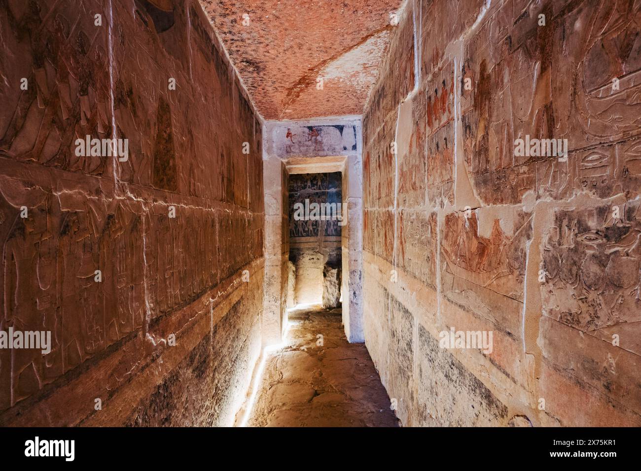 Couloir éclairé dans un tombeau mastaba Saqqara avec des reliefs peints de l'ancien Empire sur les deux murs, menant à une chambre intérieure pleine de décoration symbolique Banque D'Images