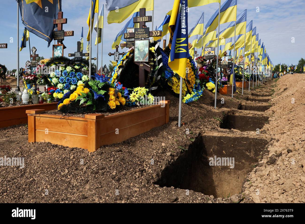 Des tombes vides nouvellement creusées sont vues par les tombes des militaires ukrainiens sur le cimetière de la ville. L'Ukraine ne donne aucun bilan officiel de ses morts de guerre - les forces armées ukrainiennes ont réitéré que leur nombre de victimes de guerre est un secret d'État. Le long de différentes sections de la ligne de front, les autorités ukrainiennes évaluent s’il faut sacrifier des hommes ou du territoire. Les responsables des services de renseignement occidentaux contestent l'estimation de Zelensky concernant les pertes en Ukraine - quelque 31 000 soldats tués dans les combats - et estiment que le chiffre est beaucoup plus élevé, probablement plus du double. Banque D'Images