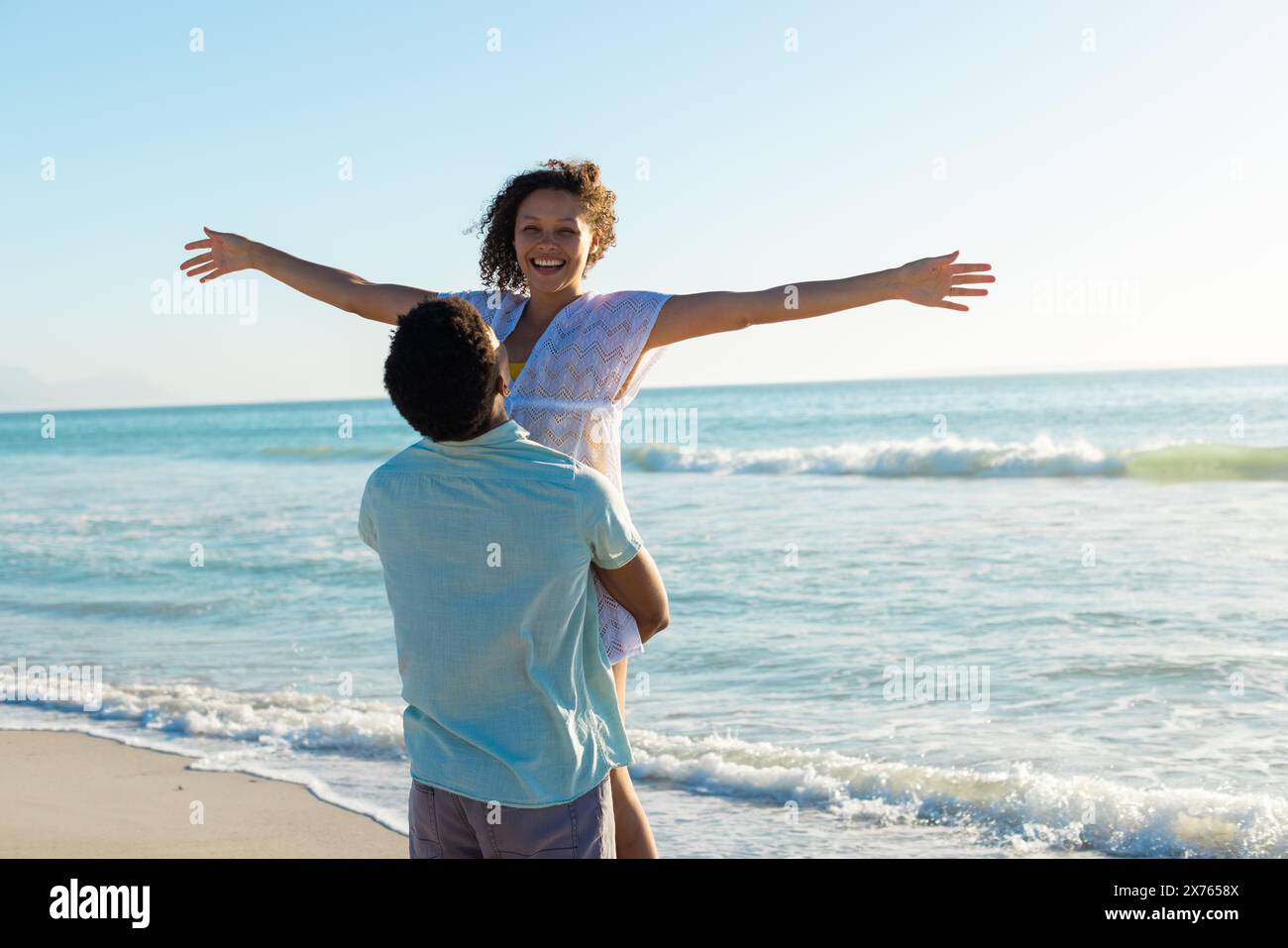 À la plage, couple biracial profitant du temps, mâle soulevant femelle Banque D'Images