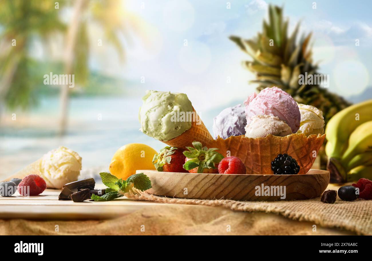 Crème glacée aux fruits assortie sur table en bois sur sable avec fond de plage tropicale Banque D'Images