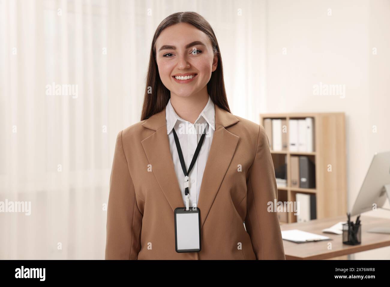 Femme heureuse avec badge vierge au bureau Banque D'Images