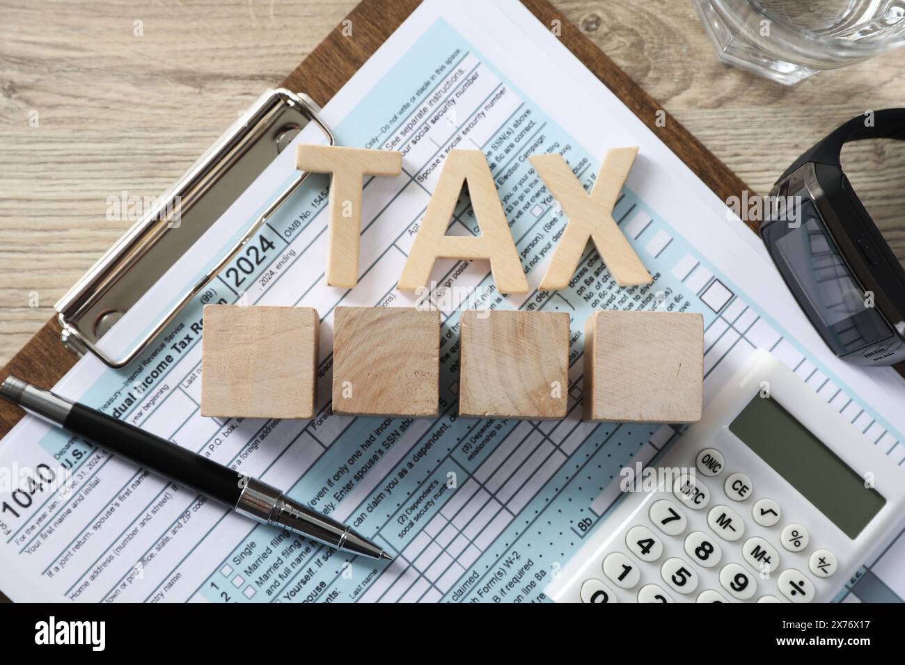 Word Tax, cubes, calculatrice, stylo et document sur table en bois, vue de dessus Banque D'Images