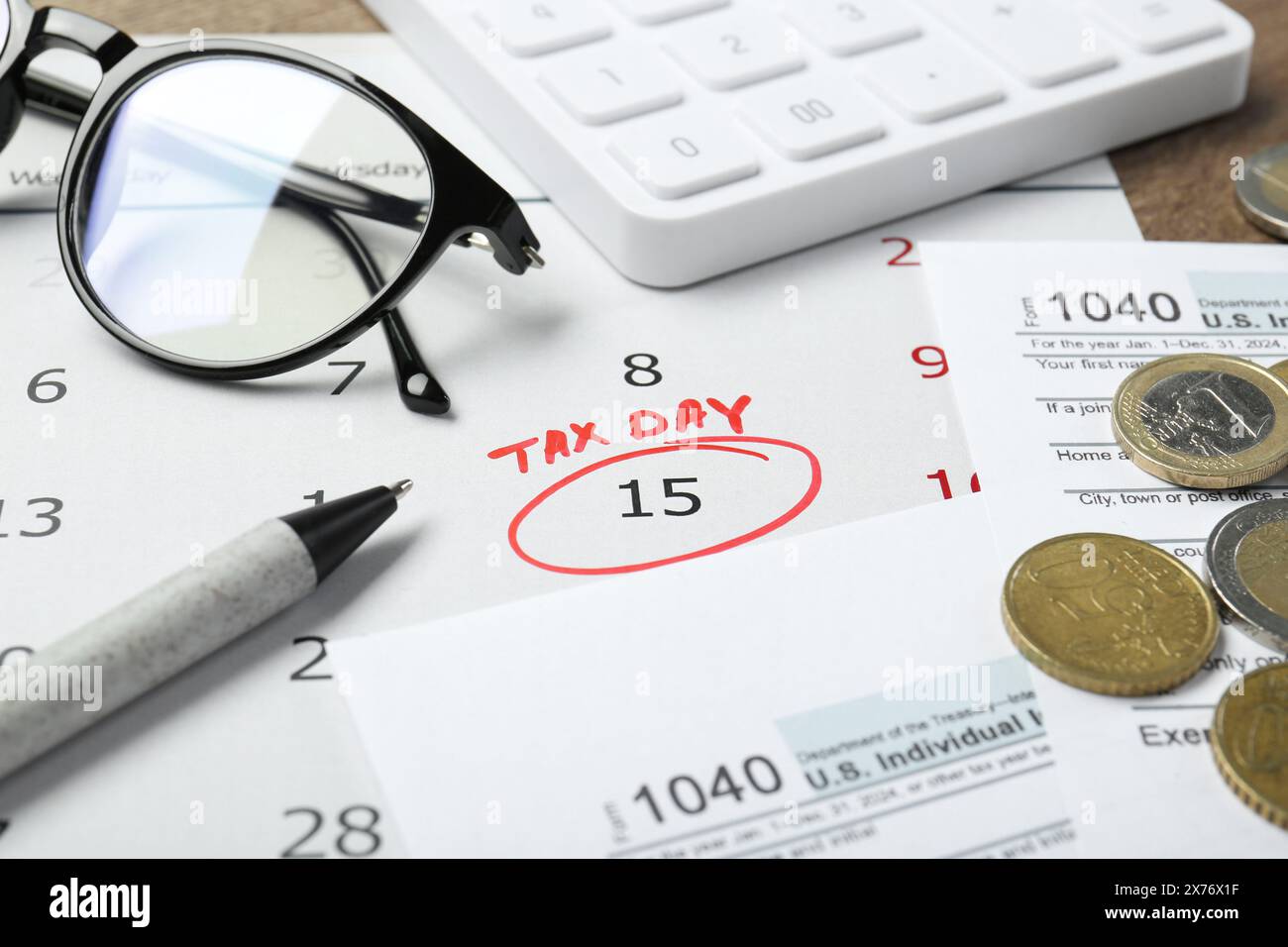 Calendrier avec rappel de date sur le jour de l'impôt, documents, stylo, pièces de monnaie, lunettes et calculatrice sur la table, gros plan Banque D'Images