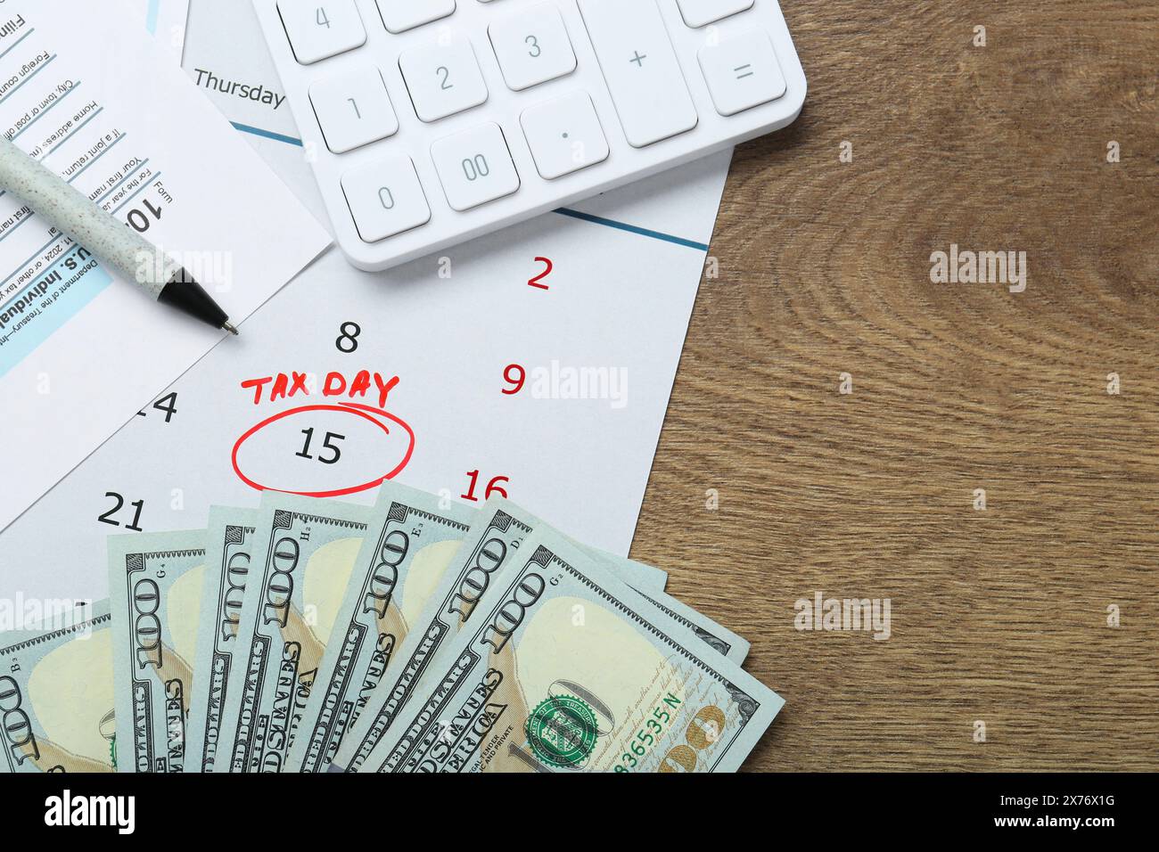 Calendrier avec rappel de date sur le jour d'imposition, documents, stylo, argent et calculatrice sur table en bois, pose à plat. Espace pour le texte Banque D'Images