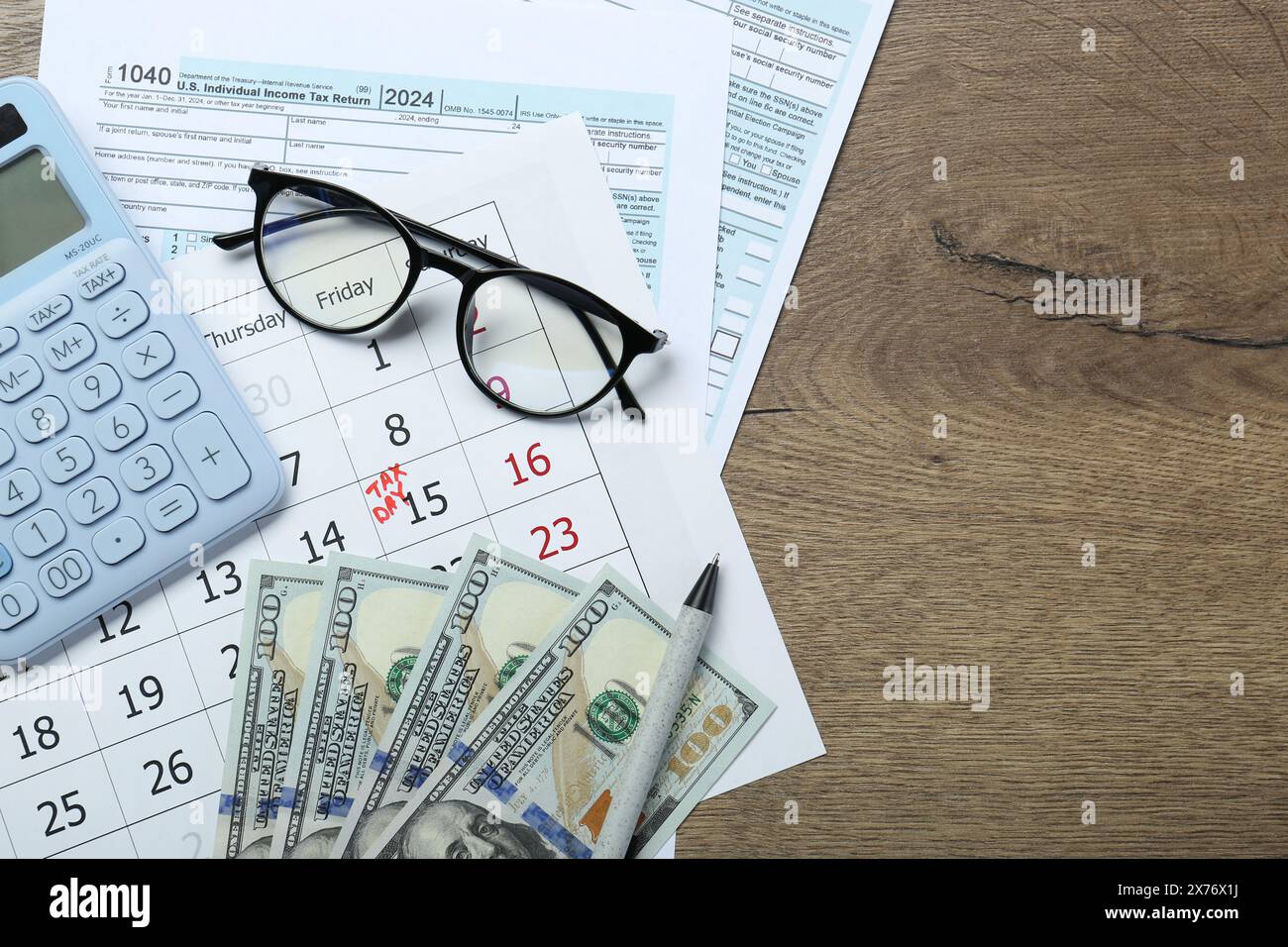 Calendrier avec rappel de date sur le jour des impôts, documents, argent, calculatrice et verres sur la table en bois, vue de dessus. Espace pour le texte Banque D'Images