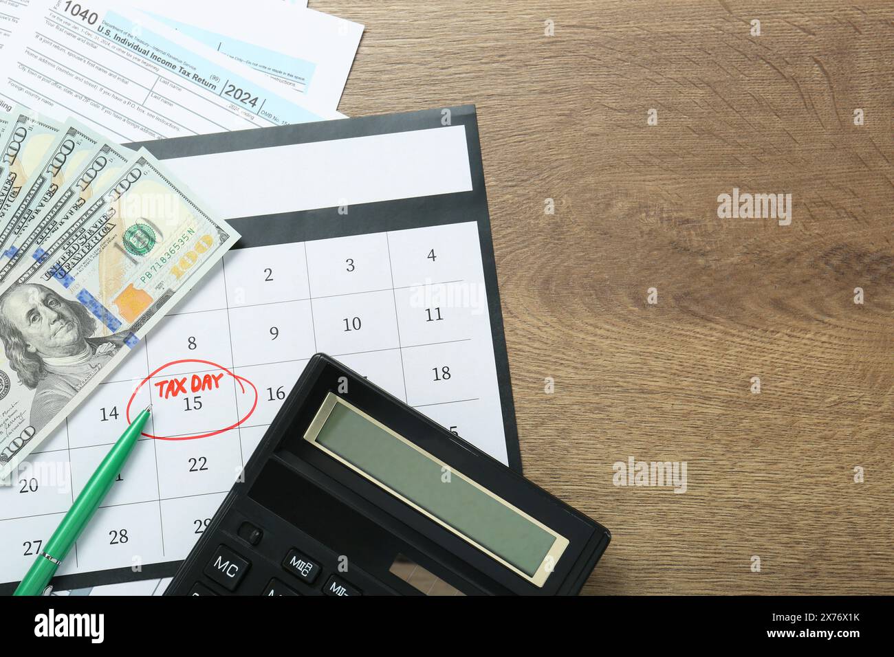 Calendrier avec rappel de date sur le jour d'imposition, documents, stylo, argent et calculatrice sur table en bois, pose à plat. Espace pour le texte Banque D'Images