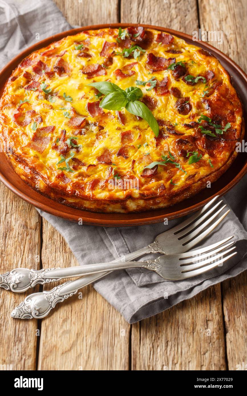 Délicieux petit déjeuner omelette avec poulet, fromage, bacon et herbes gros plan dans une assiette sur la table. Vertical Banque D'Images