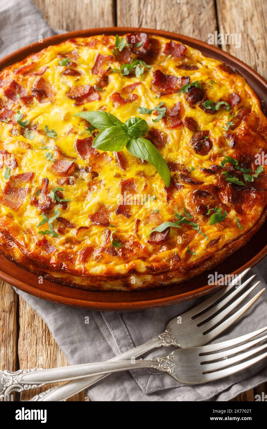 Frittata Quiche sans croûte avec bacon, poulet et fromage gros plan sur l'assiette sur la table en bois. Vertical Banque D'Images