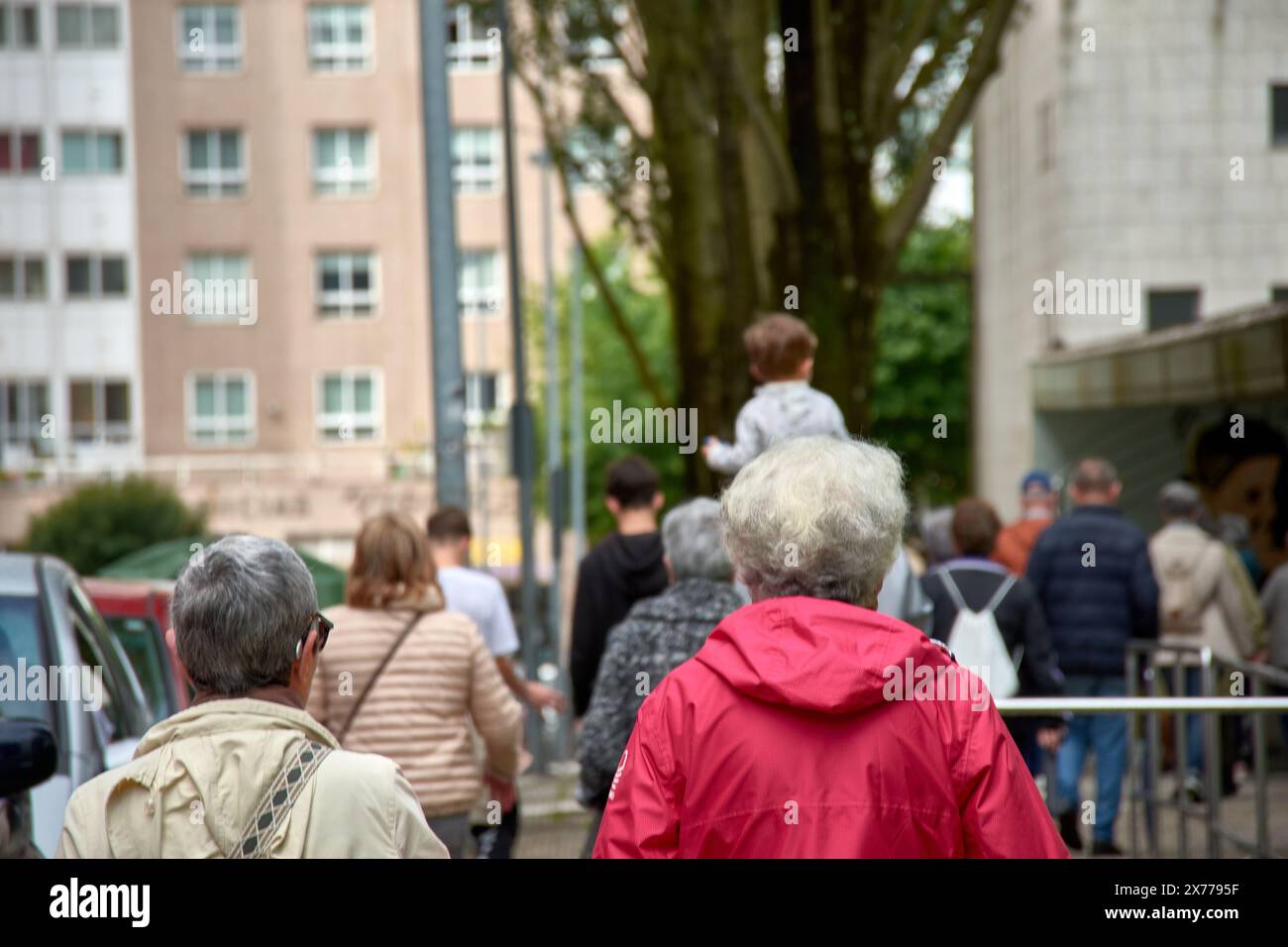 Deux femmes au dos méconnaissable marchent dans la rue en bavardant, l'une en survêtement rouge et l'autre en blanc ; elles ont toutes les deux les cheveux gris Banque D'Images