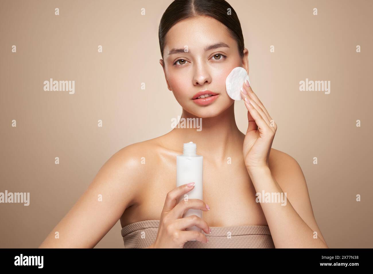 La jeune fille tient un tampon de coton tout en nettoyant le visage avec du lait cosmétique. Soin de la peau démaquillant nettoyant. Soins de base pour la peau du visage Banque D'Images