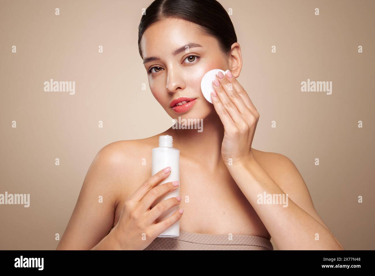 La jeune fille tient un tampon de coton tout en nettoyant le visage avec du lait cosmétique. Soin de la peau démaquillant nettoyant. Soins de base pour la peau du visage Banque D'Images