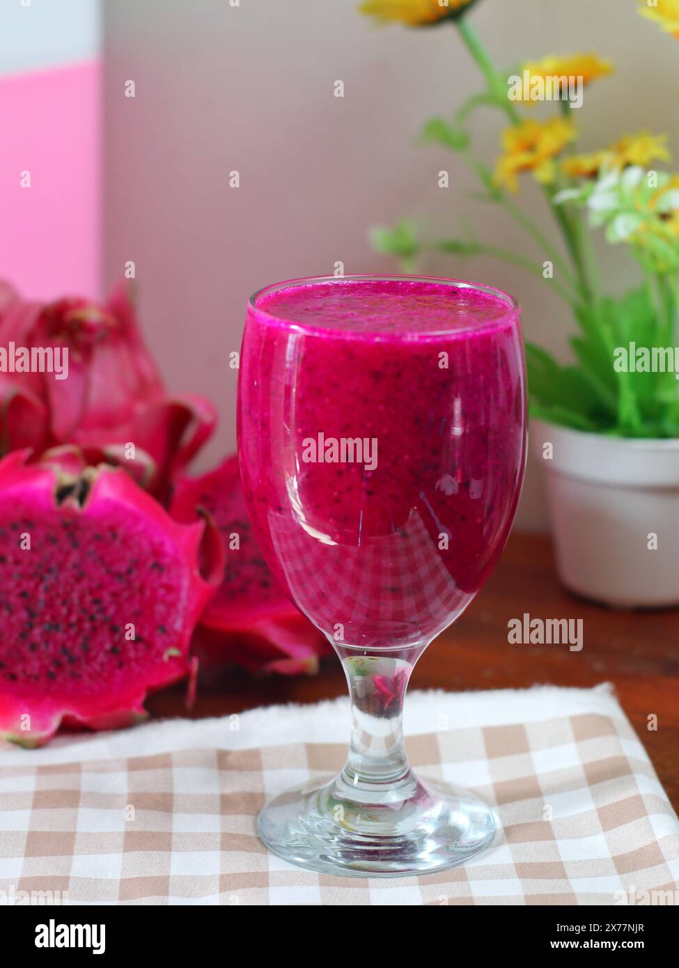 un verre de jus et des morceaux de fruit de dragon rouge sur une table décorée de tissu Banque D'Images