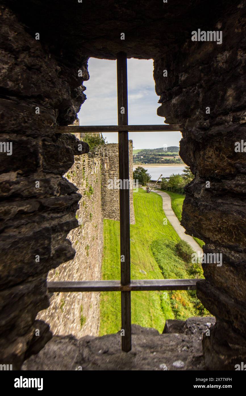 Vue à travers l'une des fentes de flèche dans les murs médiévaux de la ville de Conwy dans le nord du pays de Galles Banque D'Images