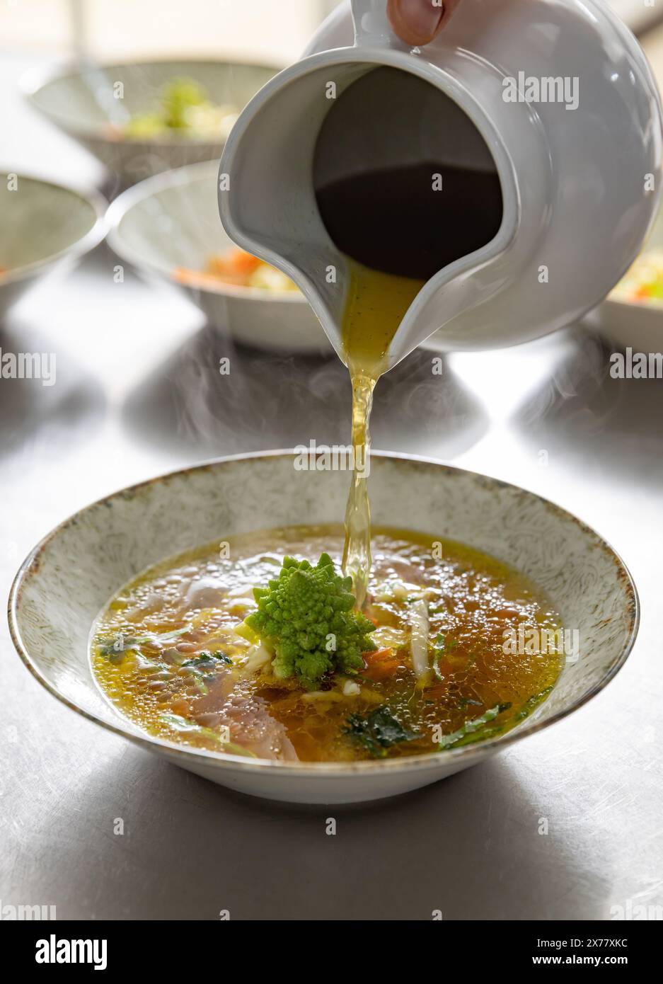 Verser le bouillon sur la salade fraîche, menu de soupe du restaurant Banque D'Images