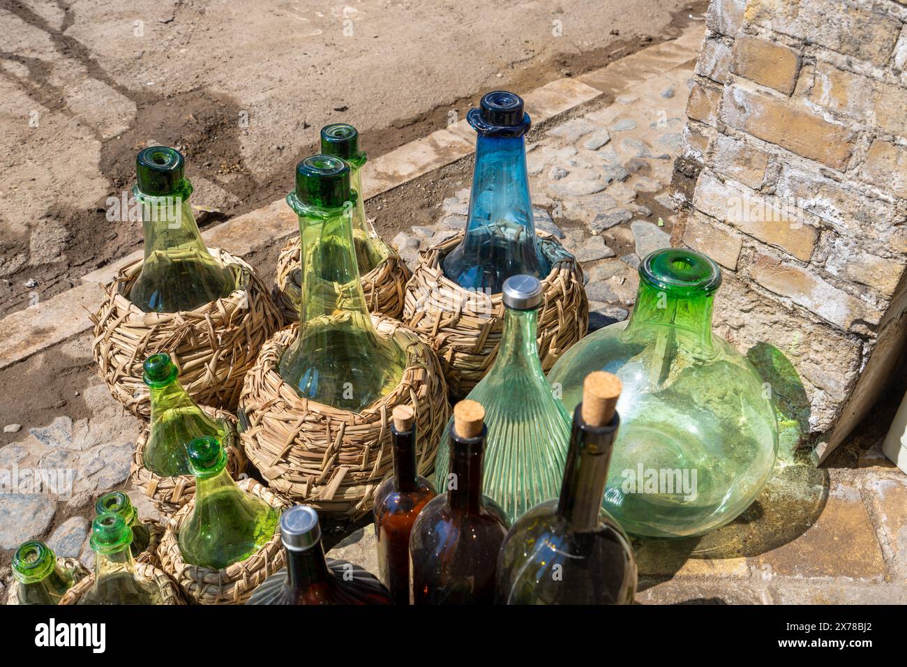 Une variété de bouteilles en verre, certaines dans des paniers tissés, sont exposées à l'extérieur du magasin. La lumière du soleil met en valeur leurs couleurs vives à Kashan, en Iran. Banque D'Images