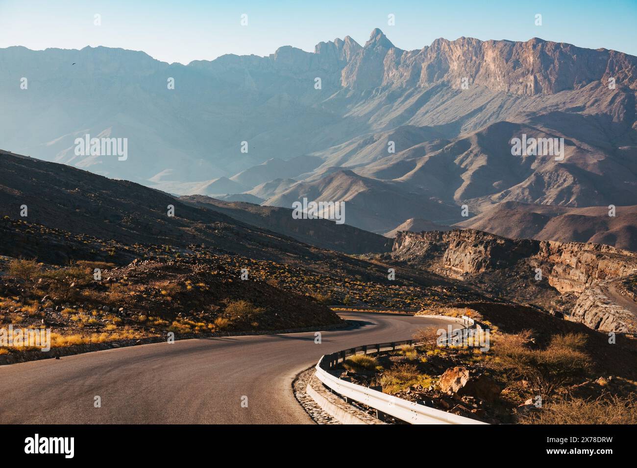 Route de montagne sinueuse à Jebel Shams, Oman, avec des sommets spectaculaires et un terrain accidenté sous la lumière douce du matin. Banque D'Images