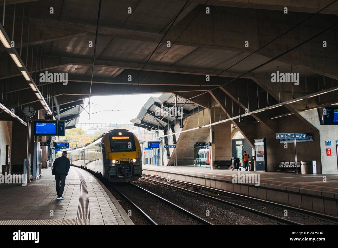 Un train à deux étages CFL moderne arrive à la gare de Pfaffenthal-Kirchberg dans la ville de Luxembourg, passant sous des auvents en béton avec une signalisation claire au-dessus Banque D'Images