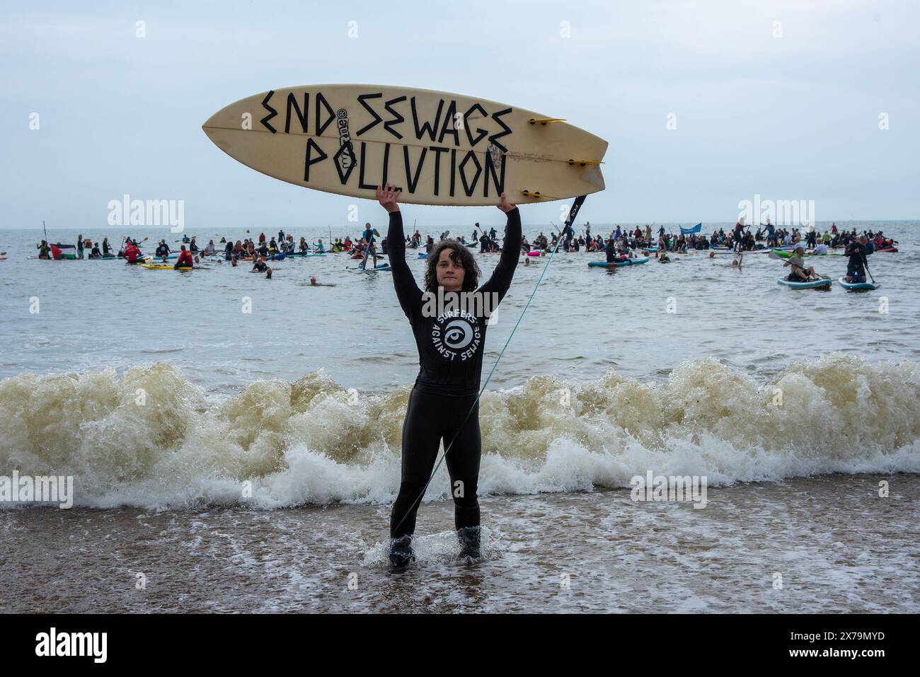 Brighton, Royaume-Uni. 18 mai 2024. Un surfeur tient une planche de surf avec un message dessus pendant la démonstration. Surfers Against Sewage a organisé une journée de protestation nationale dans tout le pays pour faire campagne contre les compagnies d'eau qui amènent les eaux usées dans les rivières et les mers britanniques. Surfeurs, plongeurs, planchistes et nageurs en mer ont rejoint la manifestation à Brighton, au Royaume-Uni. Crédit : SOPA images Limited/Alamy Live News Banque D'Images