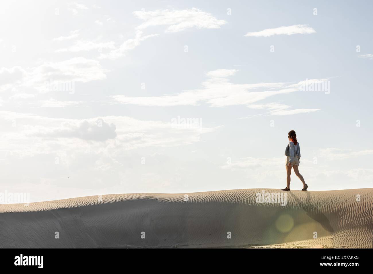 femme dans le désert marchant parmi les dunes au coucher du soleil contre le ciel, copiez l'espace dans le ciel Banque D'Images