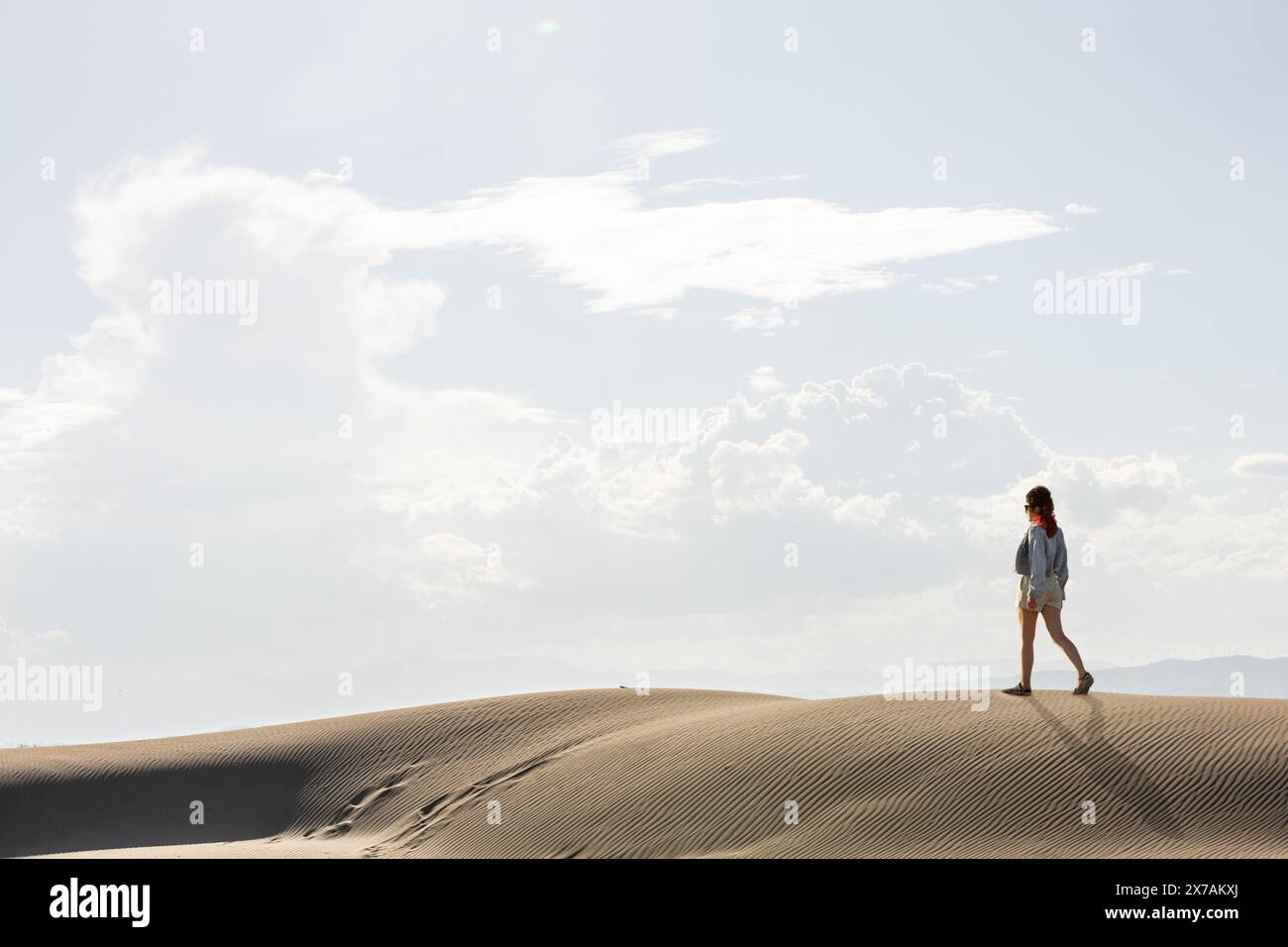 femme dans le désert marchant parmi les dunes au coucher du soleil contre le ciel, copiez l'espace dans le ciel Banque D'Images