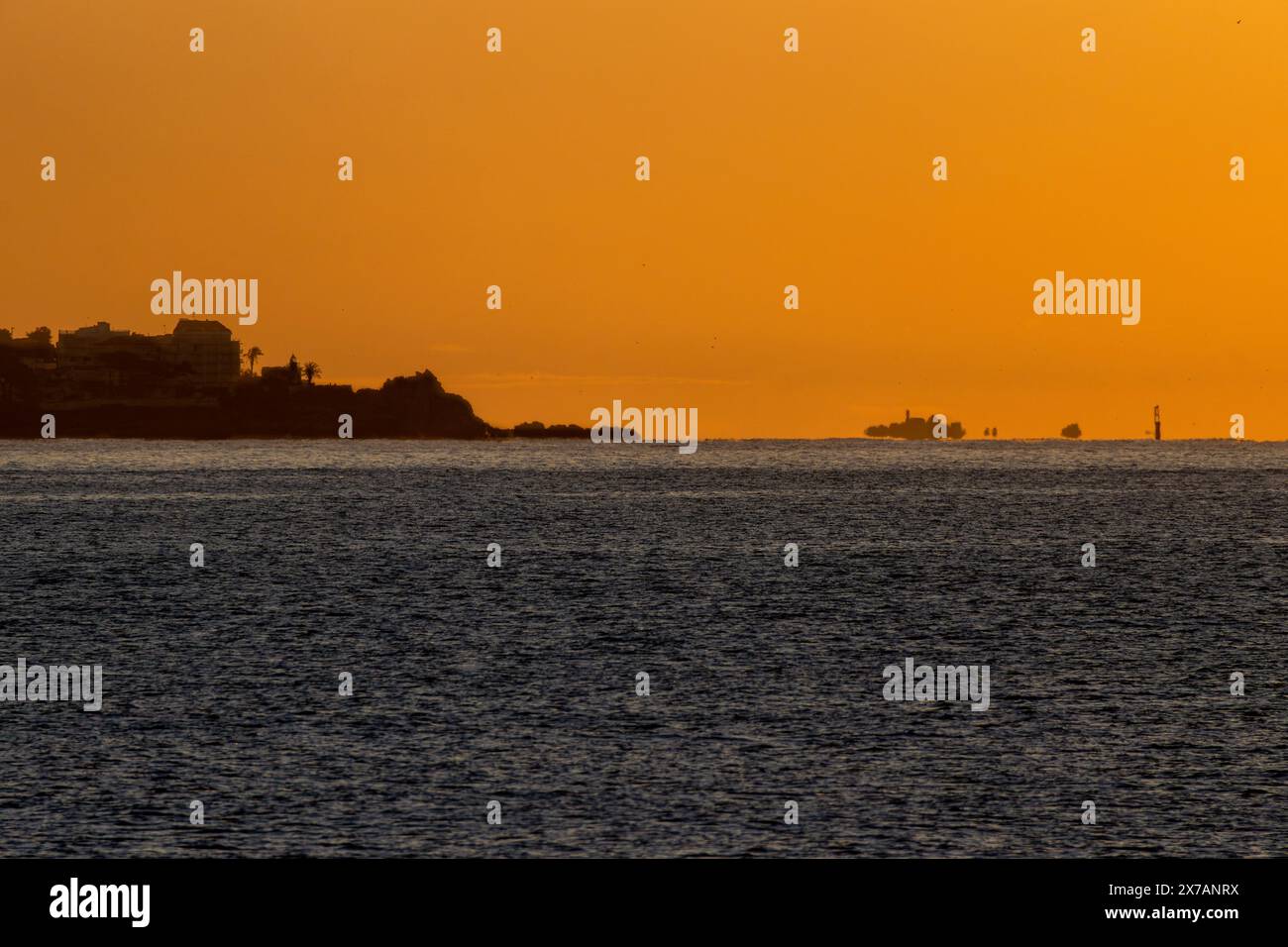 Mer Méditerranée aux eaux calmes illuminées par les premières lumières de l'aube, créant des reflets et des illusions d'optique sur la ligne d'horizon de la mer Banque D'Images