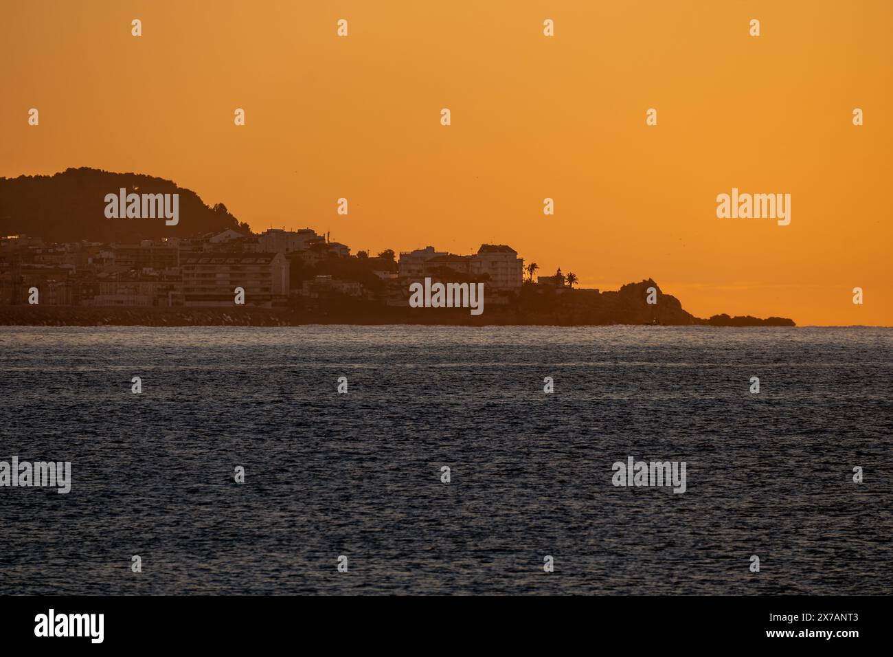 Mer Méditerranée aux eaux calmes illuminées par les premières lumières de l'aube, créant des reflets et des illusions d'optique sur la ligne d'horizon de la mer Banque D'Images