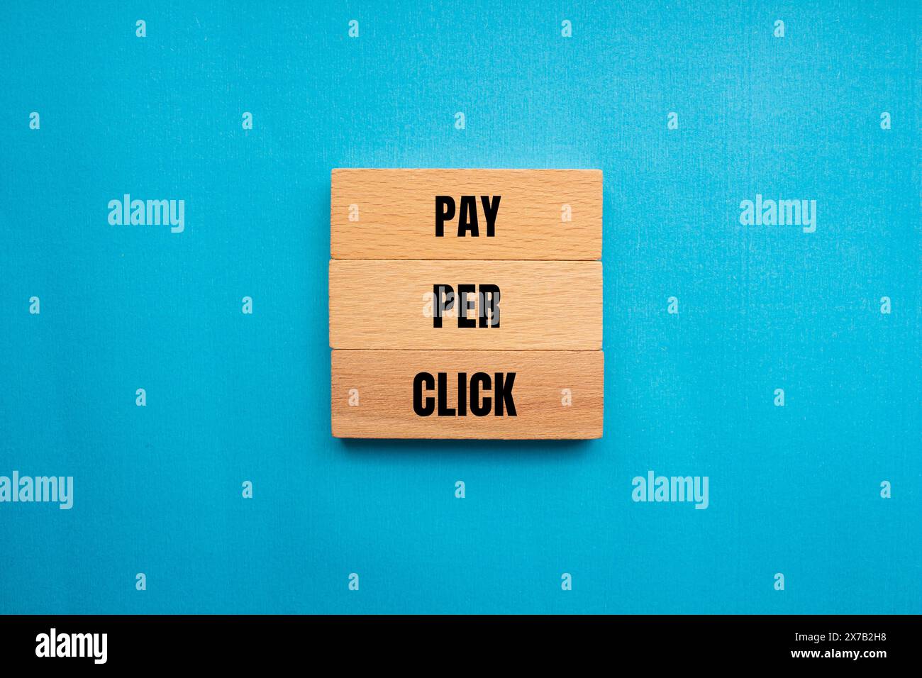Payer par clic mots écrits sur des blocs de bois avec fond bleu. Symbole PPC conceptuel de paiement par clic. Copier l'espace. Banque D'Images