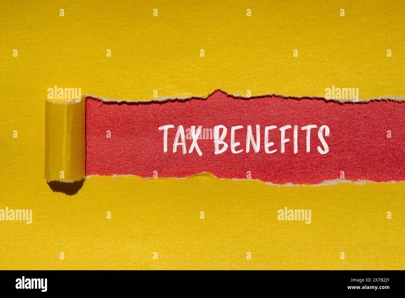 Mots sur les avantages fiscaux écrits sur du papier jaune déchiré sur fond rouge. Symbole d'avantages fiscaux conceptuels. Copier l'espace. Banque D'Images
