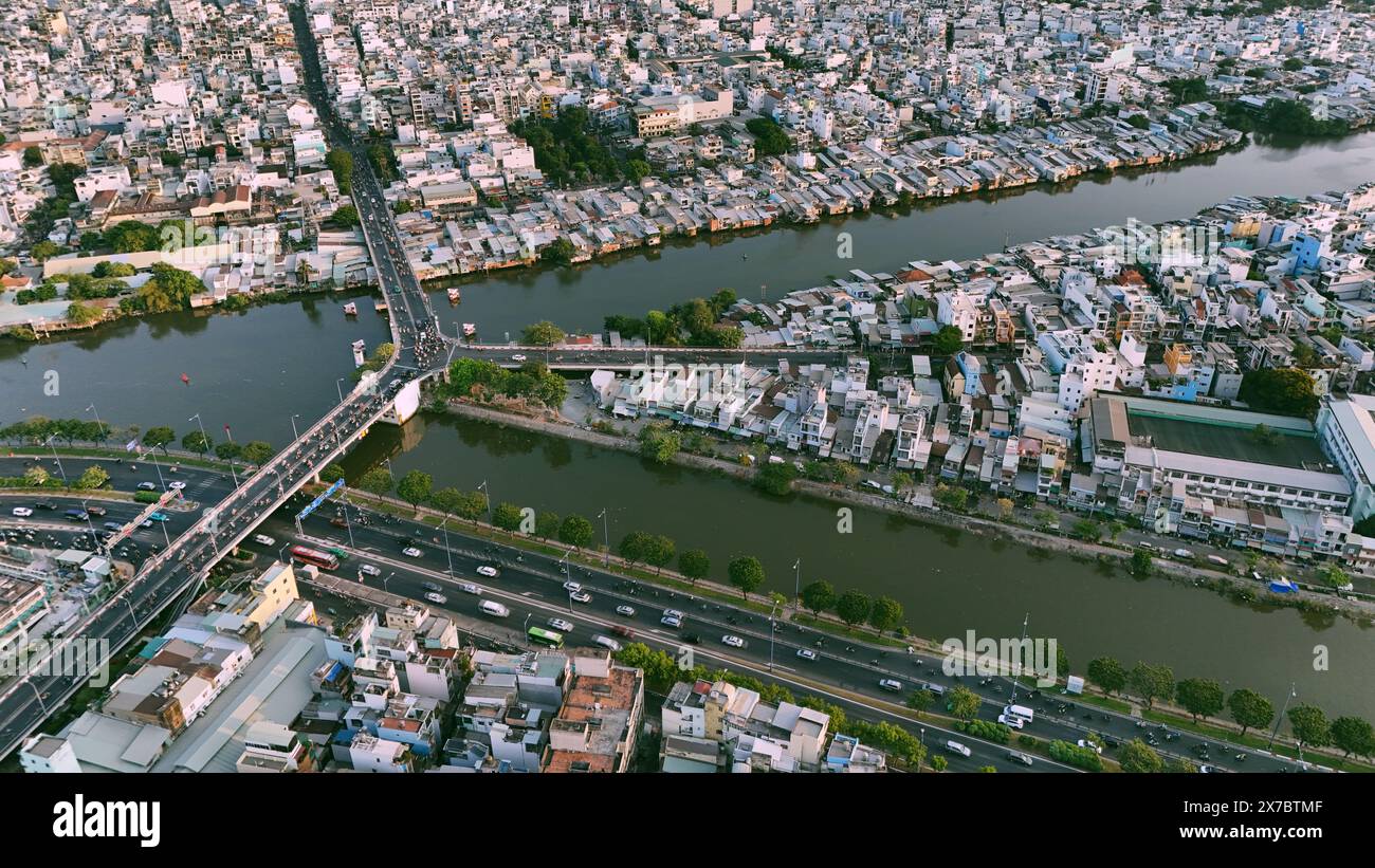 Vue aérienne depuis le drone de Ho Chi Minh, grande ville asiatique avec rangée de maison bondée, canal Nhieu Loc Thi Nghe, pont y traversant l'eau, circulation de véhicules sur ro Banque D'Images