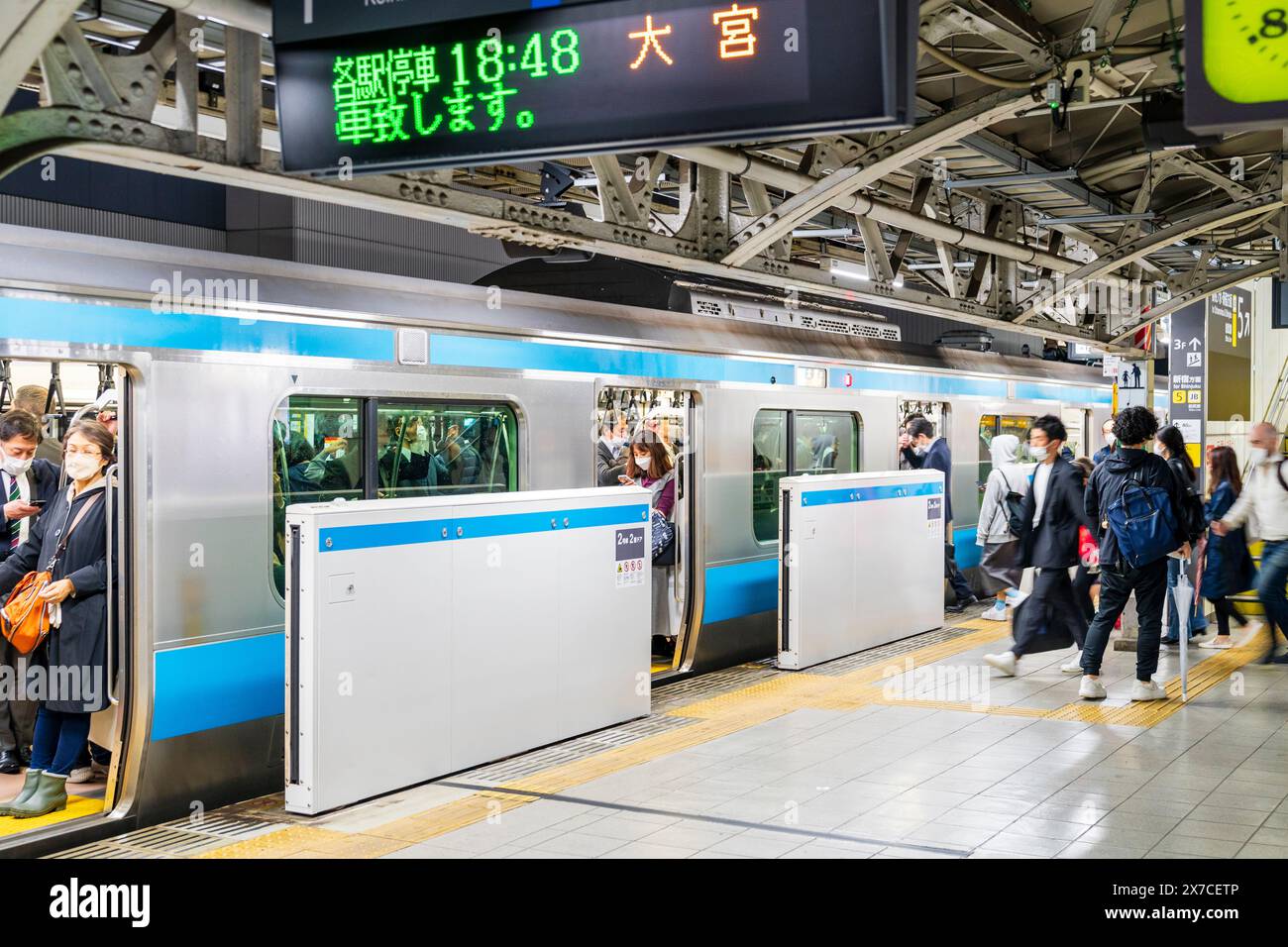 Un train de banlieue bondé sur le quai de la gare d'Akihabara à Tokyo, dans la soirée, avec des trajets de l'escalator. Banque D'Images