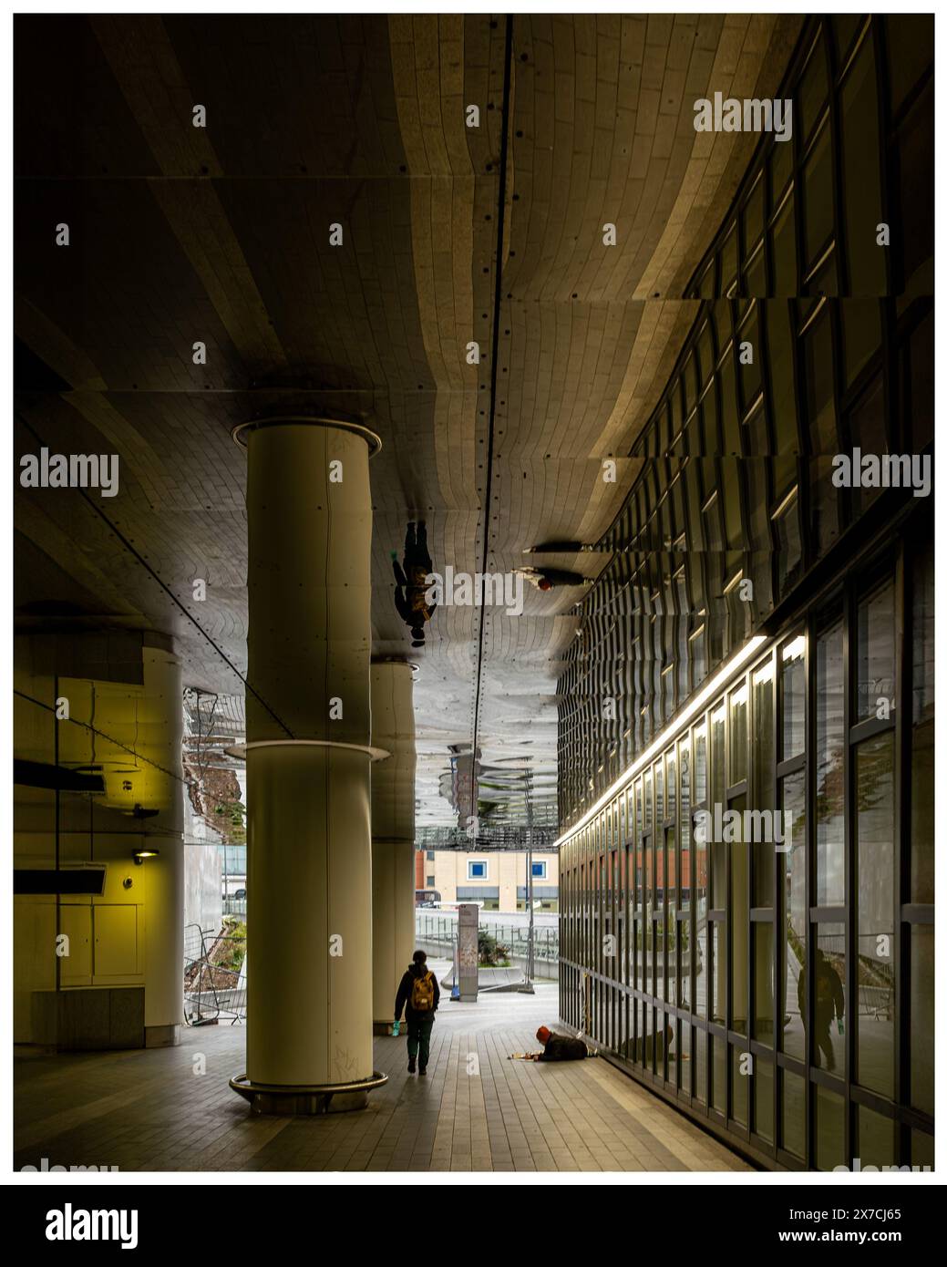 Passage de bâtiment avec colonne et plafond réfléchissant fournissant une image miroir du bâtiment et du passage et les deux personnes dans la scène Banque D'Images
