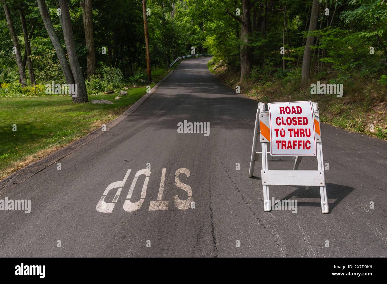 Panneau Reading Road fermé à Thru Traffic à côté du panneau d'arrêt sur la route rurale avec des arbres en arrière-plan. Banque D'Images