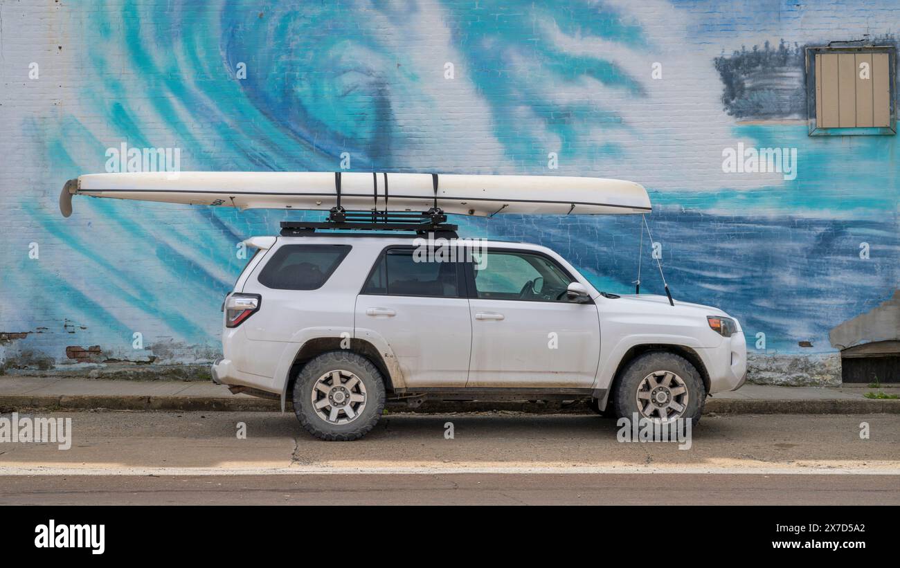 Chillicothe, Missouri, États-Unis - 22 avril 2024 : Toyota 4Runner SUV avec un canoë d'expédition sur des barres de toit contre la murale Wave. Banque D'Images