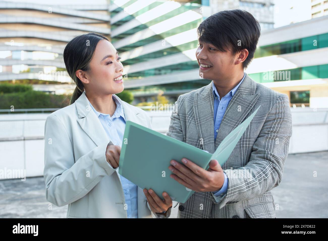 Homme d'affaires asiatique et femme tenant dossier devant le bâtiment Banque D'Images