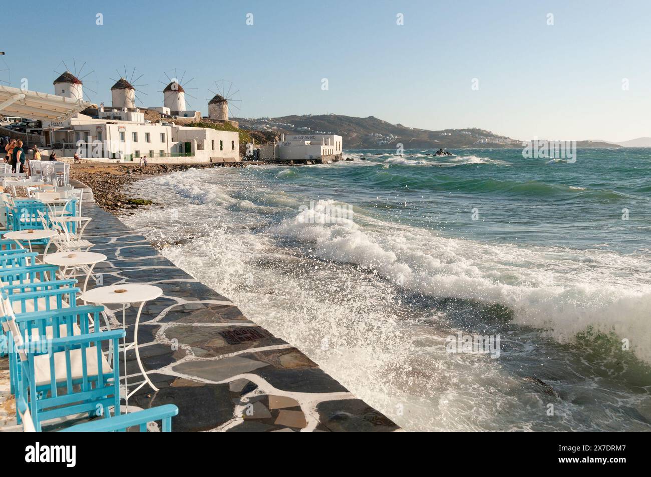 Vue panoramique depuis la promenade du moulin à vent à Mykonos par une journée ensoleillée, avec des vagues de mer agitées qui s'écrasent sur le rivage Banque D'Images