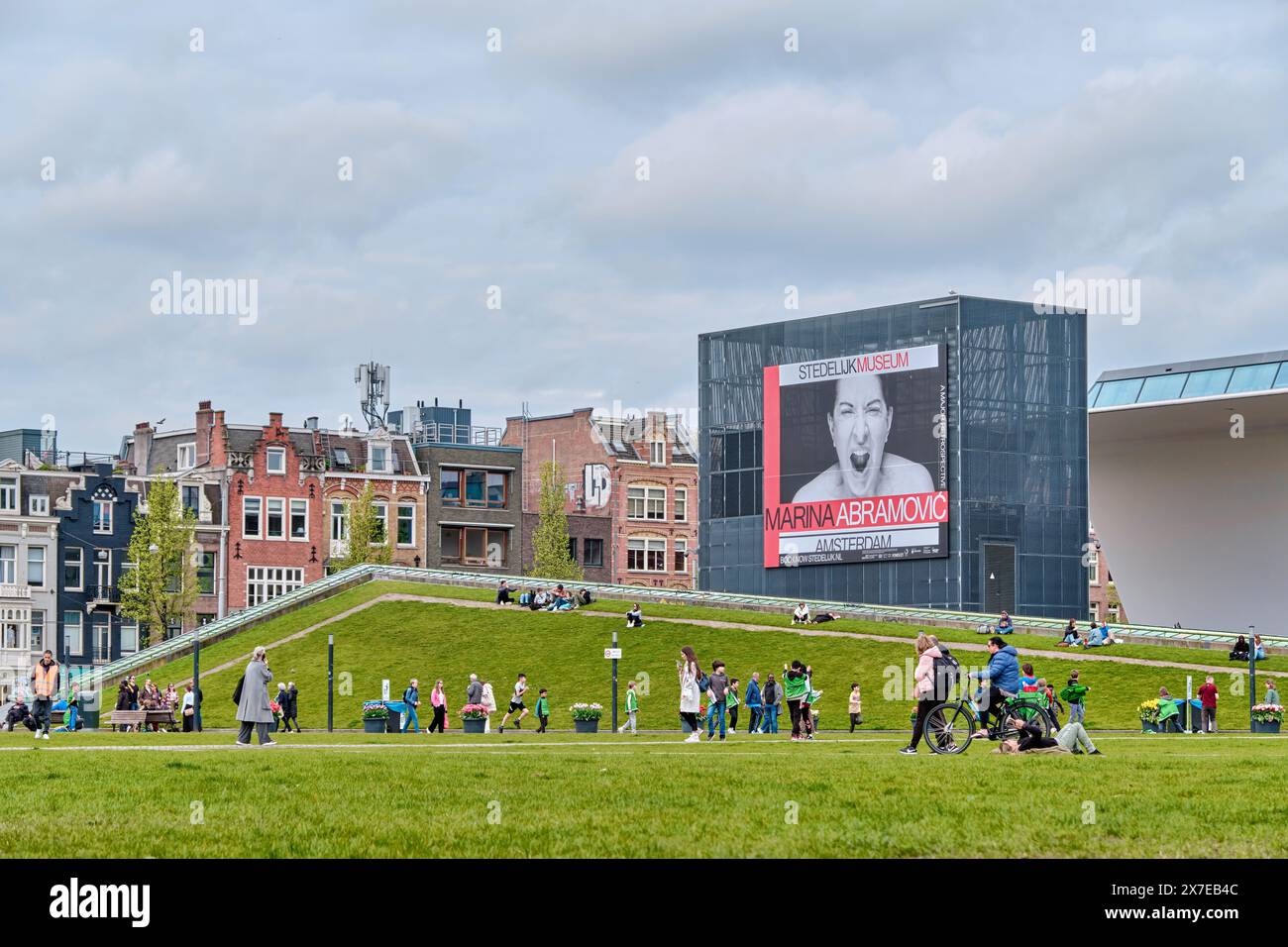 Pays-Bas, Amsterdam - 08 avril 2024 : les gens marchent et se reposent au Museumplein, devant le musée Stedelijk et l'affiche d'Abramovic Banque D'Images