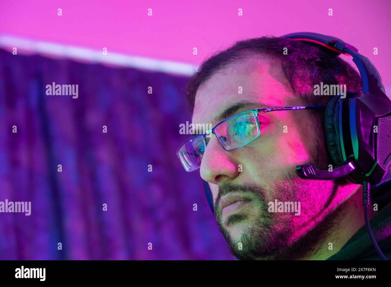 Jeune homme confiant jouant au jeu vidéo informatique en ligne, diffusion d'éclairage coloré en streaming en direct à la maison. Gamer lifestyle, E-Sport jeu en ligne tec Banque D'Images